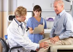 Photo of two medical professionals examining a man's knee.