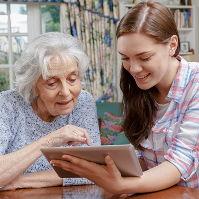 An elder and a young girl looking at a tablet