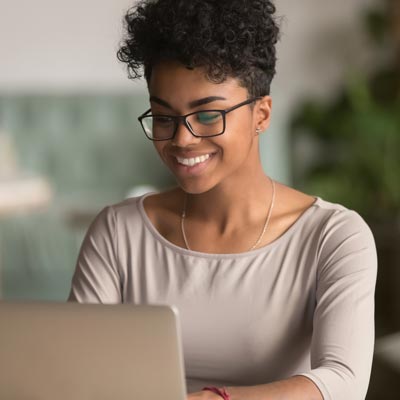 woman smiling while looking at a computer screen